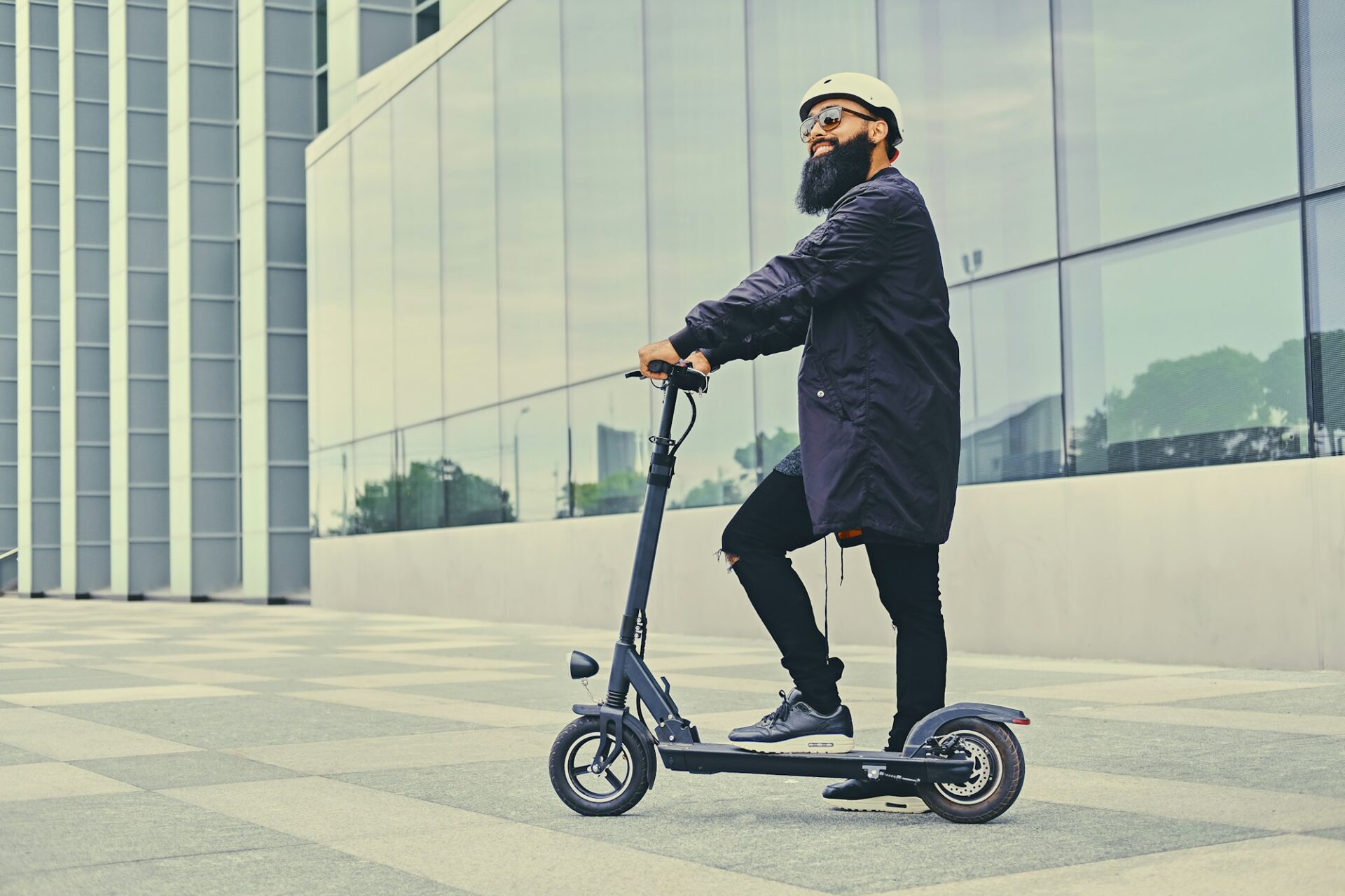 Man posing on electric scooter wearing a helmet.