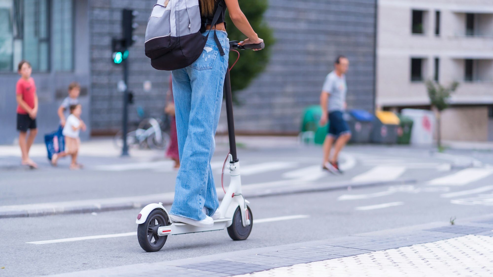 A young brunette woman moving in the city with an electric scooter, along the bike path towards the