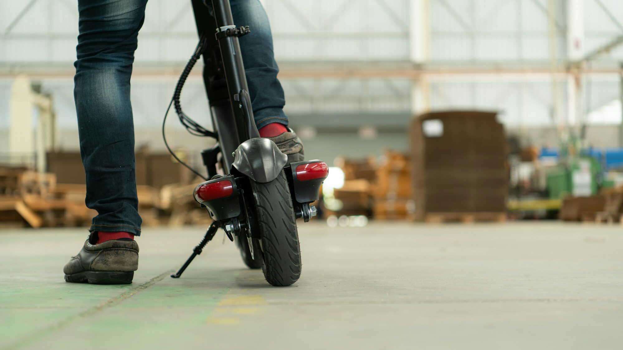 An electric scooter is parked in a large factory warehouse.