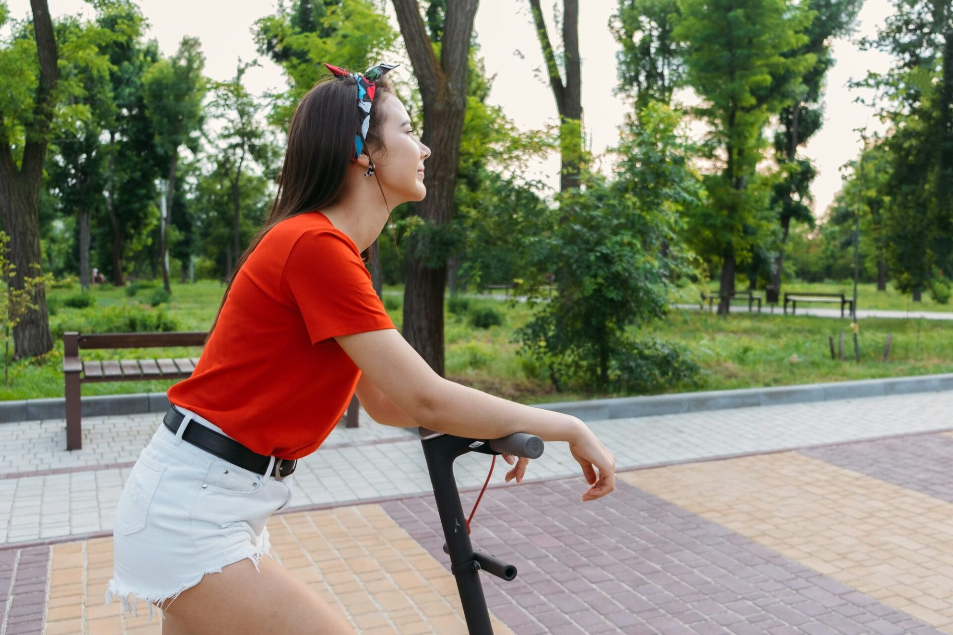 E-bikes, scooters safety. Young woman riding e scooter in urban environment. Trendy woman on