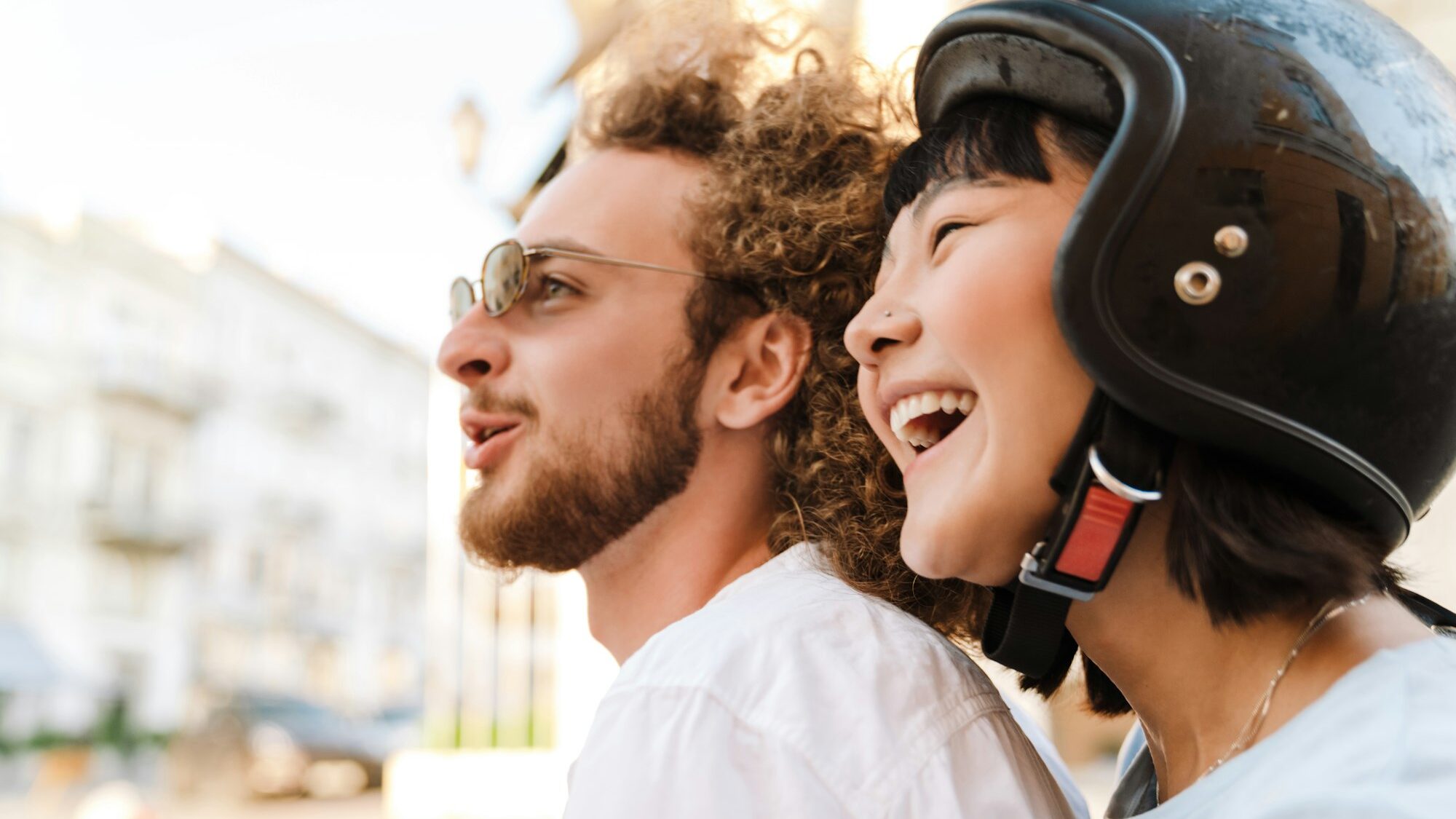 Happy young couple on scooter wearing helmet