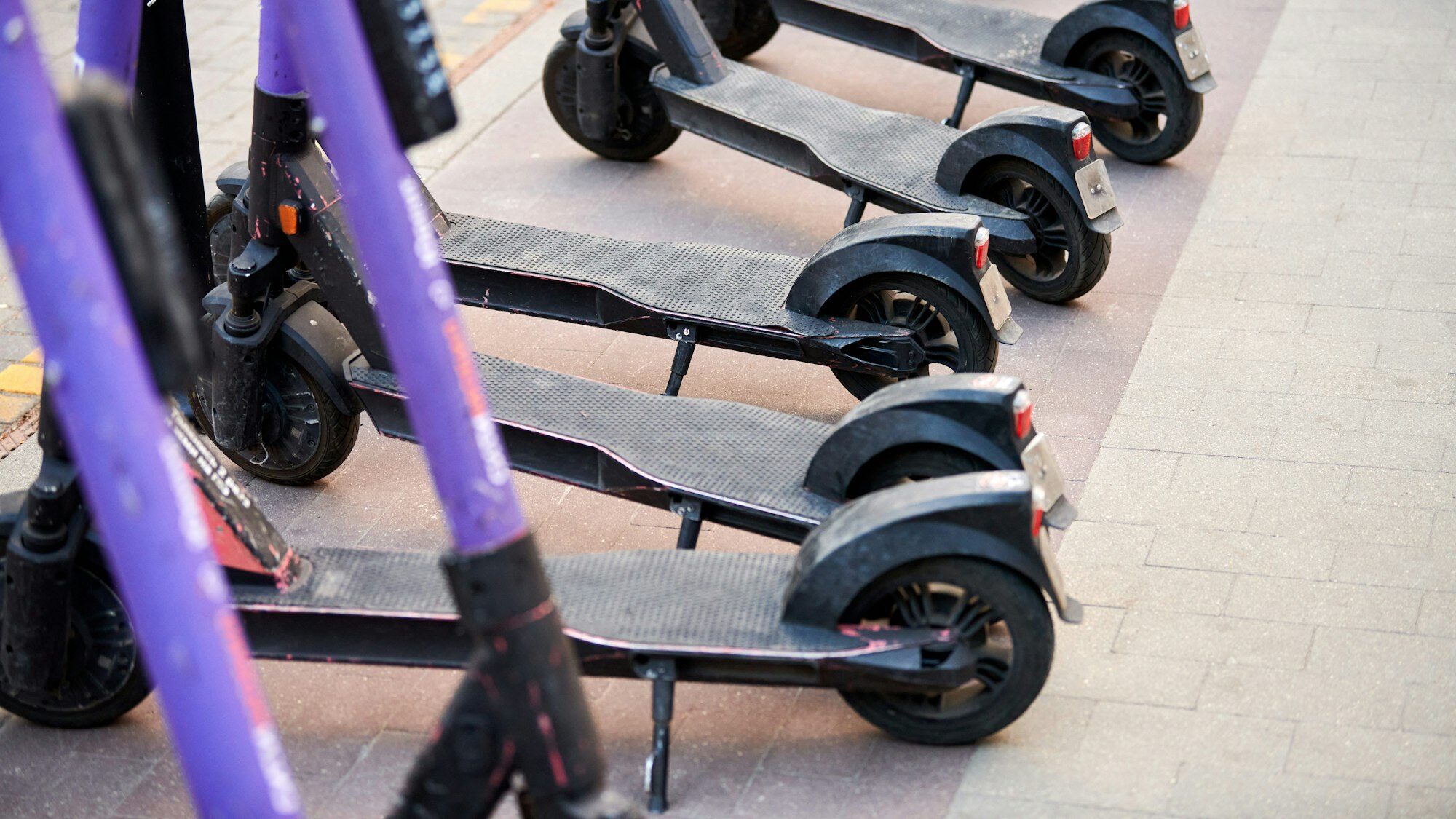 Motorized scooter parking for hourly rent on sidewalk street, vehicle for fast movement around town